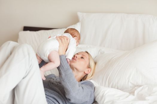 Young mother playing with her newborn in the bedroom