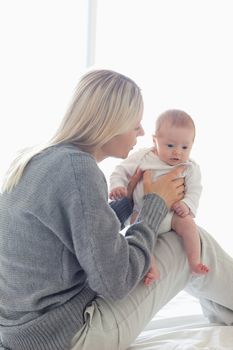 Young mom sitting with her baby on her knees