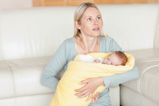 Young mother sitting with her baby in front of the couch