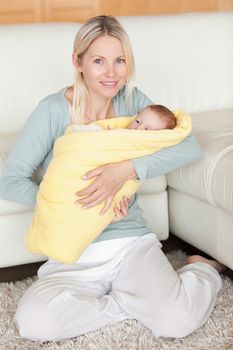 Young mother holding her baby that is wrapped into a cover