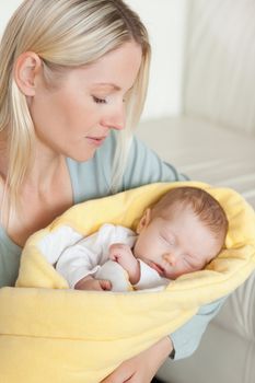 Young mother holding her sleeping baby that is wrapped up in a cover
