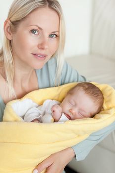 Young mom holding her sleeping baby that is wrapped up in a cover