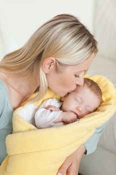 Affectionate young mother kissing her newborn's forehead