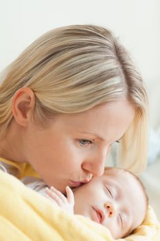 Affectionate young mother kissing her sleeping baby's cheek