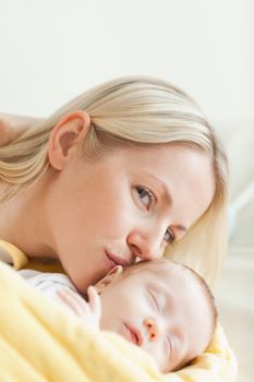 Lovely young mother kissing her sleeping baby