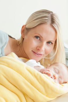 Young smiling mother relaxing next to her sleeping baby
