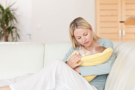 Young mother sitting on the couch with her baby in her arms