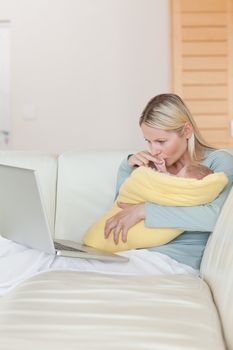 Young mother looking at her laptop while holding her baby