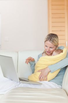 Young mother on the couch showing her baby something on the laptop