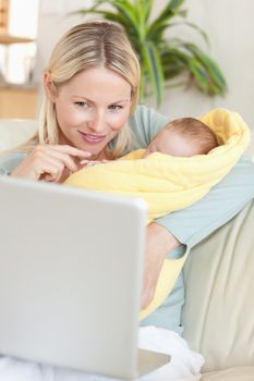 Young mother living in the living room with her baby looking at her laptop