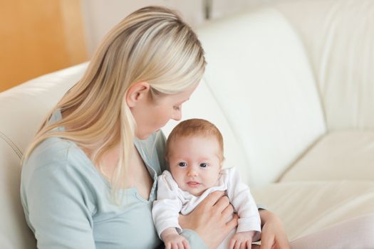 Young mother on the sofa with her newborn on her lap