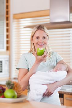 Young mother with baby on her arms having an apple