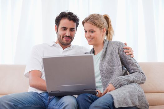 Cute couple using a notebook in his living room