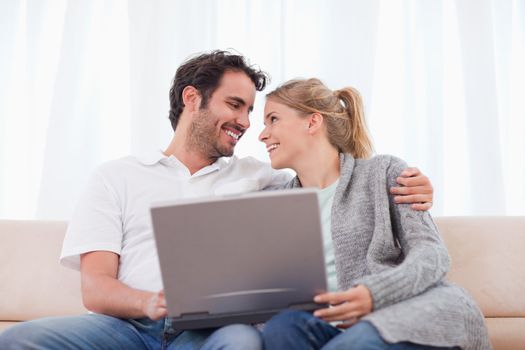 Happy couple using a laptop in their living room