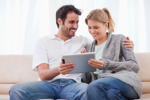 Happy couple using a tablet computer in their living room