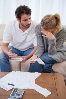 Portrait of a sad couple looking at their bills in their living room