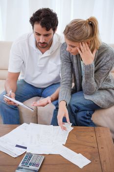 Portrait of a worried couple looking at their bills in their living room