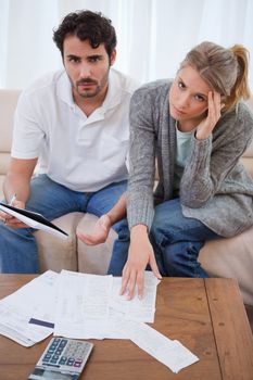 Portrait of a worried young couple looking at their bills in their living room