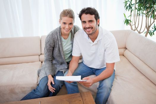 Smiling couple reading a letter in their living room