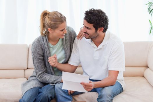 Happy couple reading a letter in their living room