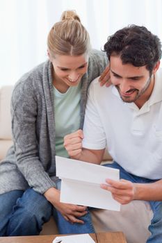 Portrait of a delighted couple reading a letter in their living room