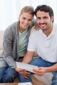 Portrait of a smiling couple reading a letter in their living room