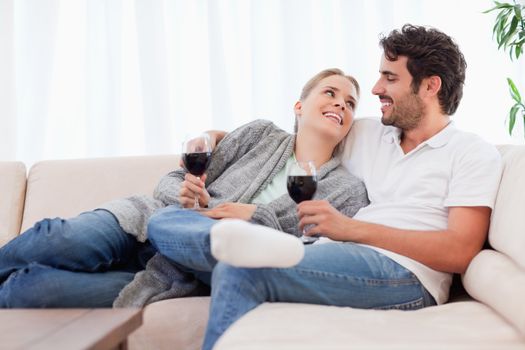 Young couple having a glass of red wine in their living room
