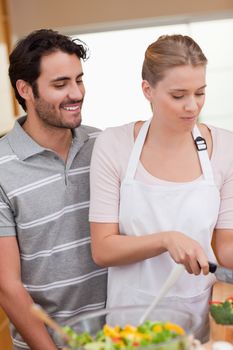 Portrait of a couple slicing pepper in their kitchen