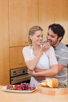 Portrait of a young couple eating fruits in their kitchen