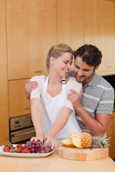 Portrait of a lovely couple eating fruits in their kitchen