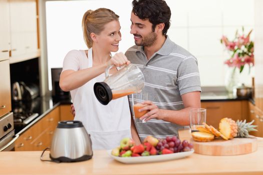 Young couple making fresh fruits juice in their kitchen