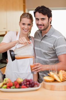 Portrait of a smiling couple drinking fruits juice in their kitchen