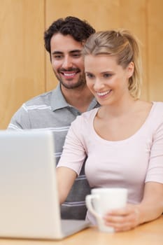 Portrait of a couple using a notebook while having coffee in their kitchen