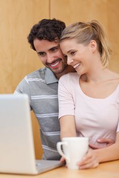 Portrait of a couple using a laptop while having tea in their kitchen