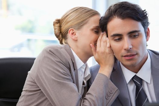 Businesswoman whispering something to her colleague in a meeting room