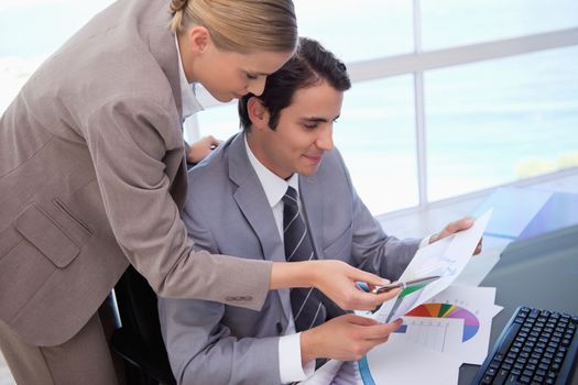 Manager pointing at something to her employee on a graph in his office