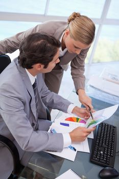 Portrait of a manager pointing at something to her employee on a graph in his office