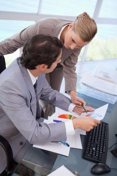 Portrait of a manager pointing at something to her secretary on a graph in his office