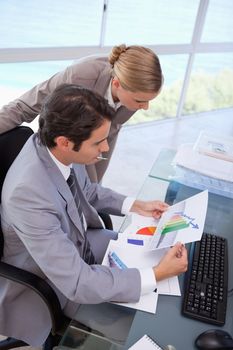 Portrait of a manager and her secretary looking at a graph in his office