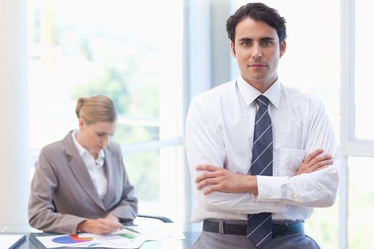 Businessman posing while his colleague is working in a meeting room
