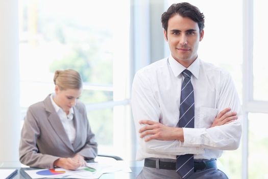 Young businessman posing while his colleague is working in a meeting room