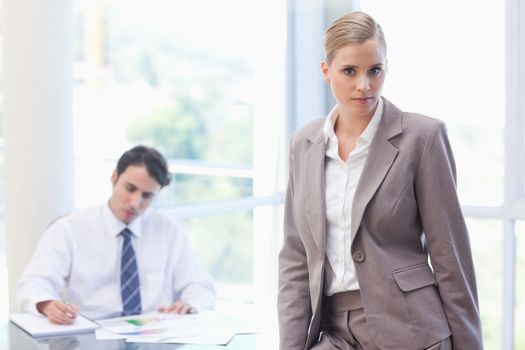 Businesswoman posing while her colleague is working in a meeting room