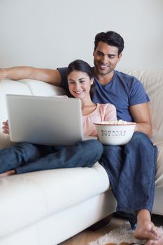 Portrait of a couple watching a movie while eating popcorn with a laptop