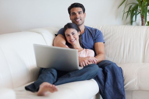 Couple watching a movie with a laptop in their living room