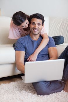 Portrait of a lovely couple using a notebook in their living room