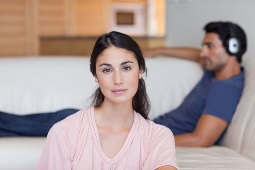 Woman posing while her boyfriend is listening to music in their living room