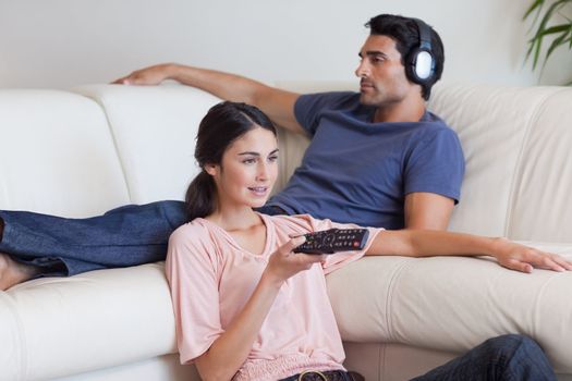 Woman watching TV while her fiance is listening to music in their living room