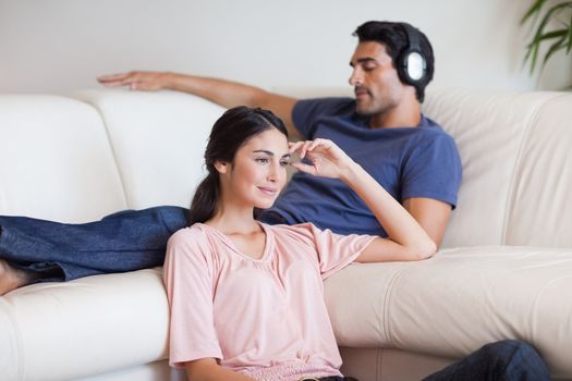 Woman watching TV while her husband is listening to music in their living room