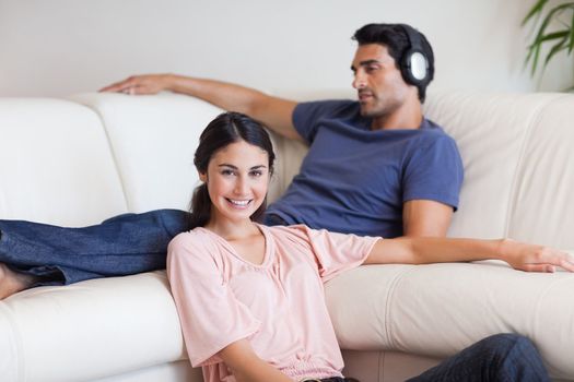 Young woman posing while her husband is listening to music in their living room