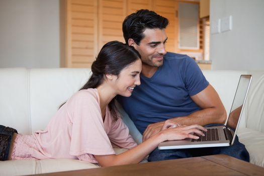 Smiling young couple using a laptop in their living room